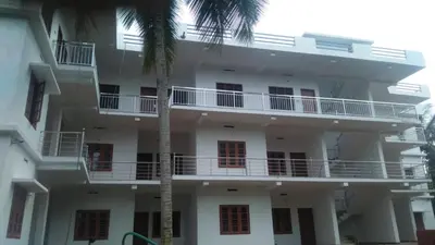 a white building with a palm tree in front of it at Wayanad Biriyomz Residency, Kalpatta, Low Cost Rooms and Deluxe Apartment in Kalpetta