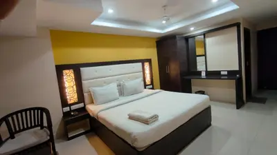 a bedroom with a large bed and a mirror at PPH Living TriColours Hotel Gandhipuram in Coimbatore
