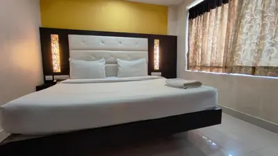 a bedroom with a large white bed with a window at PPH Living TriColours Hotel Gandhipuram in Coimbatore