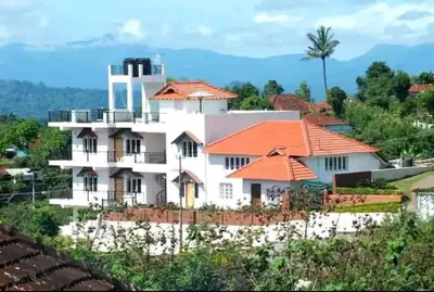a large white house with an orange roof at New Hill Valley Family Homestay-WiFi-View in Madikeri