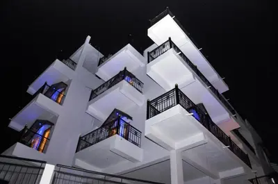 a white building with balconies and lights on it at New Hill Valley Family Homestay-WiFi-View in Madikeri