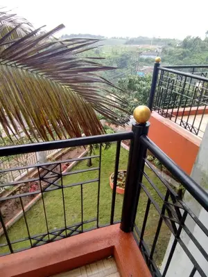 a view from the balcony of a house with a palm tree at New Hill Valley Family Homestay-WiFi-View in Madikeri