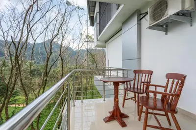 a balcony with two chairs and a table with a view at Mscb guest house in Idukki