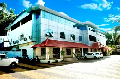 a building with cars parked in front of it at BROAD BEAN Chakkarakkal in Chakkarakkal