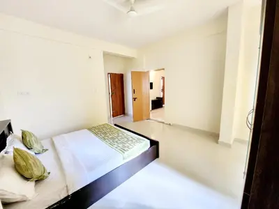 a white bedroom with a bed and a mirror at Suyog Apartments in Mysore