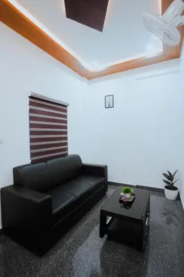 a living room with a black couch and a table at BEVERLY SUITES in Wayanad