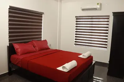 a bedroom with a red bed with red pillows and a window at BEVERLY SUITES in Wayanad