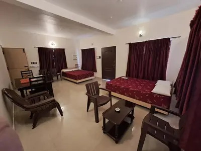 a room with two beds and a table and chairs at ATTUVAM VISTA in Kodaikānāl