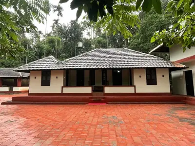 a building with a tile roof and a brick courtyard at Deesha Homes in Wayanad