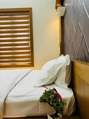 a bed with white sheets and a plant on a table at Milaano Orchids, Service Villa, Kammana Mananthavady in Wayanad