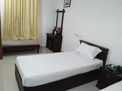 a bedroom with a bed and a chair in a room at MP RESIDANCY in Perintalmanna