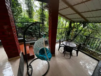 a porch with a hammock and a table on a balcony at Coorg Vismaya in Madikeri