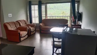 a living room with chairs and a couch and a table at Green Valley Holiday Home in Meppādi