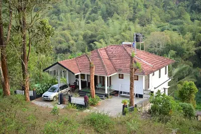 a house with a car parked in front of it at Green Valley Holiday Home in Meppādi