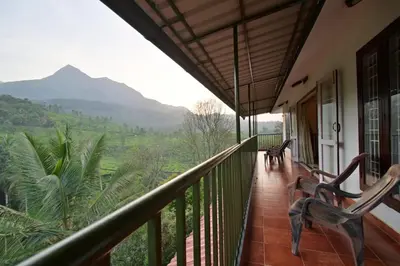 a balcony of a house with a view of the mountains at Green Valley Holiday Home in Meppādi