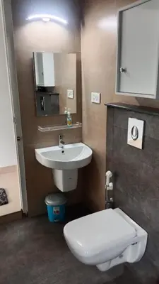a bathroom with a white toilet and a sink at Green Valley Holiday Home in Meppādi