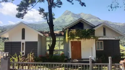 a house with a mountain in the background at Green Valley Holiday Home in Meppādi
