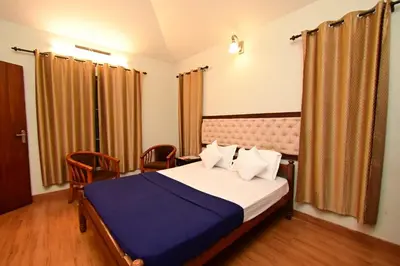 a bedroom with a bed and chairs in a room at Green Valley Holiday Home in Meppādi