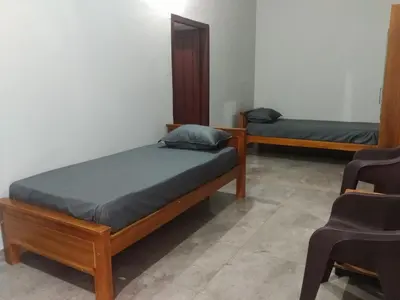 two beds in a room with a chair at Malapuram quarters in Malappuram