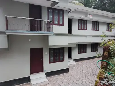 a white building with red doors and a courtyard at Malapuram quarters in Malappuram