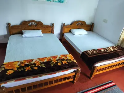 two twin beds in a room withacers at Madan Homestay in Napoklu