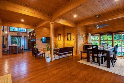 a dining room and living room of a log cabin at amã Stays & Trails The Malabar Villa Heliconia, Kozhikode in Wayanad