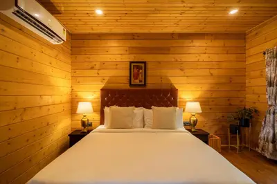 a bedroom with wooden walls and a bed with two lamps at amã Stays & Trails The Malabar Villa Heliconia, Kozhikode in Wayanad