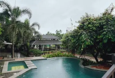 a swimming pool in front of a building with trees at Royad Calicut Farm House - Premium Villa with Pool Inside a Farm in Kozhikode