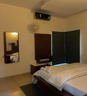 a bedroom with a bed with a mirror and a fan at Royad Calicut Farm House - Premium Villa with Pool Inside a Farm in Kozhikode