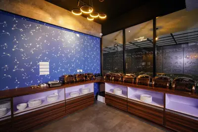a restaurant with a blue wall with a display of dishes at Lantern Apart Hotel in Perintalmanna