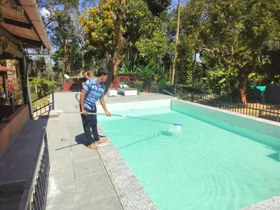 a man holding a net in a swimming pool at Devi Villa - Plantation Retreat and Forest Getaway in Kutta