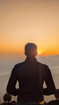 a man standing on top of a mountain looking at the sunset at Crossroads Hostel 1957 in Wayanad