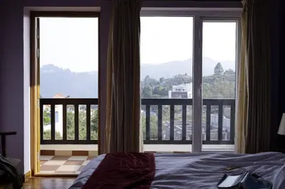 a bedroom with a bed and a view of a balcony at PURPLE ORCHID BY XACRO XPERIENCES in Kodaikānāl