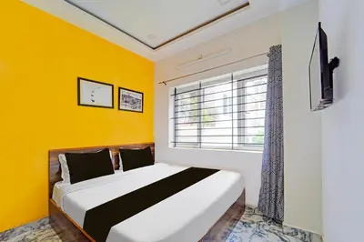 a bedroom with a bed with yellow walls and a window at Super Hotel O Vijaynagar Road Formerly Anmol Peace Stay in Ooty