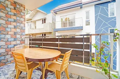a patio with a wooden table and chairs on a balcony at Super Hotel O Vijaynagar Road Formerly Anmol Peace Stay in Ooty