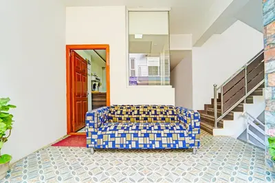 a blue and yellow couch in a room with stairs at Super Hotel O Vijaynagar Road Formerly Anmol Peace Stay in Ooty