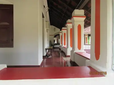 an empty corridor of a building with red and white walls at Srivilas in Pudunagaram