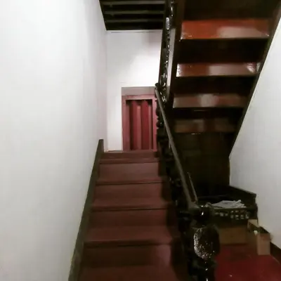 a stairway with wooden stairs and a red door at Srivilas in Pudunagaram