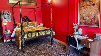 a bedroom with a bed in a red wall at Habba Kadal Kashmiri Heritage Hotel & Hub in Coonoor