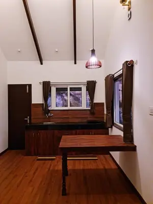 a room with a wooden table and a window at Sky Sketch in Kodaikānāl