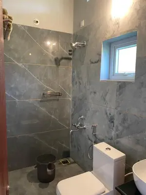 a bathroom with a white toilet and a shower at FernHills Homestay in Madikeri