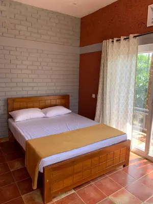 a bed in a bedroom with a large window at FernHills Homestay in Madikeri