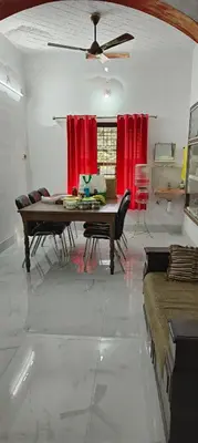 a living room with a table and red curtains at 3 bedroom country home with a lush full backyard in Trichūr