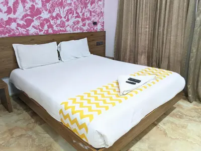 a bed with a yellow and white blanket on it at Cherai Blue View Beach Resort in Cochin