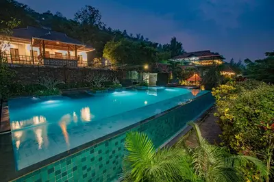 a swimming pool in front of a house at night at Oxyvalley Resort in Attappādi