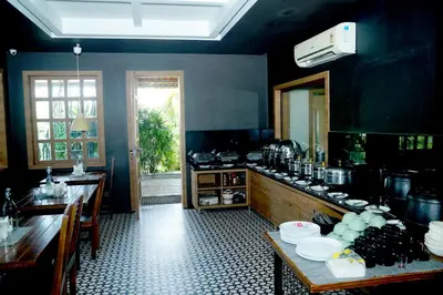 a large kitchen with a table and a counter top at Oxyvalley Resort in Attappādi