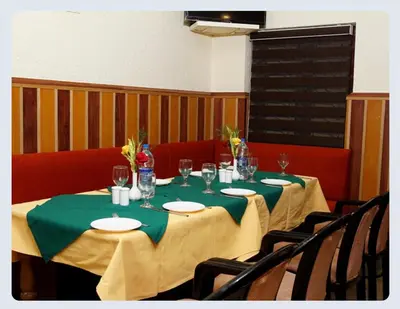 a table with a green table cloth and wine glasses at Hotel Sasthapuri in Kozhikode