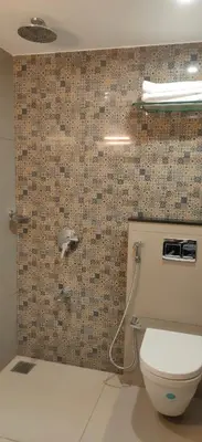 a bathroom with a toilet and a tile wall at HILUX COURTYARD in Palakkad