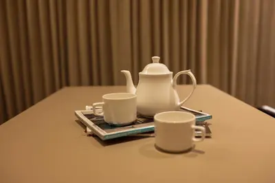 a tea pot and two cups on a table at HILUX COURTYARD in Palakkad