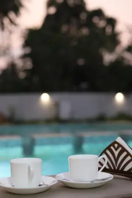two cups of coffee sitting on a table near a pool at Seeheim Resorts in Athirappilly